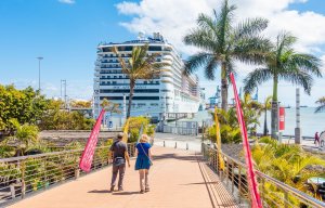 a couple walking on a bridge with a cruise ship in the background