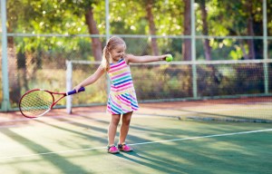 a little girl is holding a tennis racquet and a tennis ball