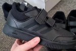 a person is holding a pair of black adidas shoes