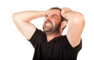 a man with a beard is holding his head in pain