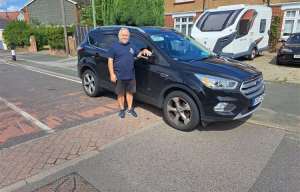 a man is standing next to a black suv on the side of a road .