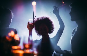 a woman with an afro is holding a drink in her hand