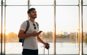 a man standing in front of a window looking at his phone